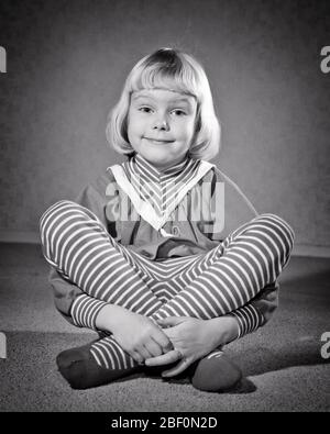 ANNÉES 1950 FILLE BLONDE ASSISE À PATTES CROISÉES PORTER DES COLLANTS LEOTARD À RAYURES REGARDANT L'APPAREIL PHOTO - J4670 DEB001 HARS STRIPED STUDIO SANS SANTÉ ACCUEIL VIE COPIE ESPACE DEMI-LONGUEUR RAYURES CONFIANCE EXPRESSIONS B&W OEIL BONHEUR STYLES SOURIANTS SOURIRES COLLANTS JOYFUL LEOTARD ÉLÉGANT LARGE EYED DEB001 EXPRESSION FACIALE INTELLIGENTE FASHIONS CROISSANCE JEUNES LEGGINGS À PATTES NOIR ET BLANC ORIGINE CAUCASIENNE À L'ANCIENNE Banque D'Images