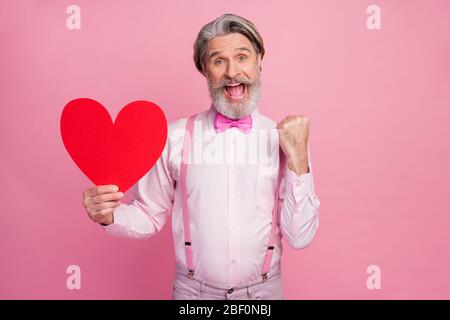 Portrait de son beau et attrayant imposant chanceux gai gai gai homme à poil gris tenant dans les mains grand grand coeur célébrant la fête festale isolé Banque D'Images