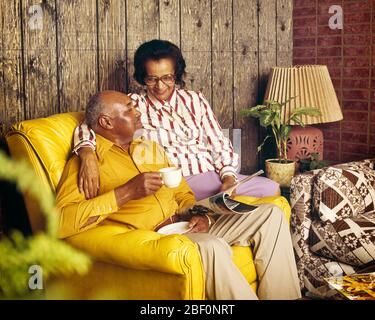 ANNÉES 1970 1980 COUPLE AFRO-AMÉRICAIN MÛR ASSIS SUR CUIR JAUNE CHAISE BOIRE CAFÉ HOLDING MAGAZINE LAMBRISSÉ CHAMBRE - KF12714 PHT001 HARS COULEUR JAUNE AÎNÉS VIEUX TEMPS NOSTALGIE VIEILLE MODE RETRAITÉ 1 STYLE DE COMMUNICATION INFORMATION FORTE JOIE DE VIVRE SATISFACTION AÎNÉS FEMMES RAYURES ÉPOUSE ÉPOUX MARIS MAISON VIE COPIE ESPACE AMITIÉ DEMI-LONGUEUR FEMMES PERSONNES SOINS HOMMES RAYURES RETRAITE HOMME SENIOR ASSOCIÉ ADULTE SENIOR FEMME SENIOR RETRAITÉ BONHEUR OLDSTERS HAUTE ANGLE OLDSTER LOISIRS SALLE DE SÉJOUR AFRO-AMÉRICAINS BLOUSE NOIRE AFRO-AMÉRICAINE À PANNEAUX ANCIENS Banque D'Images