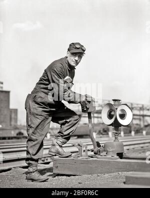 HOMME DES ANNÉES 1930 OUVRIER DU CHEMIN DE FER SWITCHMAN REGARDER LE RÉGLAGE DE LA CAMÉRA COMMUTATEUR DE VOIE FERRÉE PARTICIPATION PAR LEVIER DE DÉPLACEMENT MANUEL - R6157 HAR001 COMPÉTENCE DU HARS BRAS DE COMPÉTENCE LEVIER DE COMPÉTENCES AVERTISSEMENT MANUEL DIRECTION PROFESSIONS POINTS DE GUIDE COMMUTATION MILIEU ADULTE MOYENNE-ADULTE PARTICIPATION FEMME NOIR ET BLANC CAUCASIEN ETHNICITÉ HAR001 MÉCANISME VIEUX RAILS FAÇONNÉS Banque D'Images