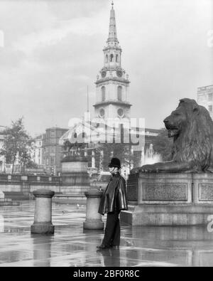 1930 JOUR DE PLUIE LONDON BOBBY DEBOUT PRÈS DE LA STATUE DU LION TRAFALGAR SQUARE ST. ÉGLISE ANGLICANE MARTIN-IN-THE-FIELDS EN B/G ANGLETERRE - R7643 HAR001 HARS RAINY LION PERSONNES HOMMES TRADITIONNELS PLEURANT OFFICIER SUIVANT ANGLAIS B&W GRANDE CDP PROTÉGER ET SERVIR HAUTE PROTECTION FORCE COURAGE FIERTÉ AUTORITÉ OCCUPATIONS UNIFORMES CONCEPTUEL BOBBY ST. POLICIERS DE LA POLICE DE LA VILLE ANGLICANE DE WESTMINSTER COPS COIFFURES MI-ADULTE HOMME DE MI-ADULTE JEUNE HOMME BADGE HOMME ADULTE BADGES NOIR ET BLANC CAUCASIEN GRANDE-BRETAGNE HAR001 EMBLÉMATIQUE À L'ANCIENNE TRAFALGAR ROYAUME-UNI Banque D'Images