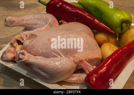 Ferme le poulet et les légumes crus dans un bol blanc prêt à cuisiner Banque D'Images