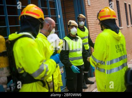 Les pompiers et les membres de l'urgence militaire de l'armée espagnole (EMU) portant un équipement de protection comme mesure préventive parlent à l'extérieur du centre de santé. Les membres de l'unité militaire d'urgence de l'armée espagnole (UME) et les pompiers désinfectent un centre de santé après le confinement décrété par le gouvernement espagnol et qui sera prolongé jusqu'au 10 mai. Banque D'Images