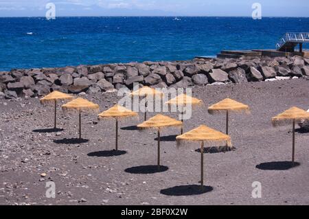 Une zone avec des parasols de paille sur la plage près de la côte attend les baigneurs au soleil de midi Banque D'Images
