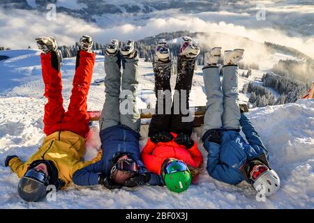 Les skieurs se trouvent dans la neige et étirent leurs jambes dans l'air, les montagnes enneigées, le télésiège dans le domaine skiable de SkiWelt Wilder Kaiser Brixental, Brixen Banque D'Images