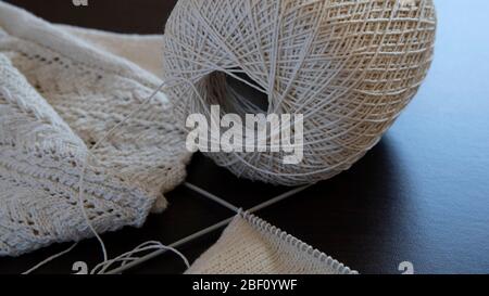 Gros plan d'un tissu tricoté avec une boule et des aiguilles Banque D'Images