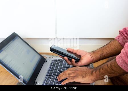 Espace de travail de fortune où un homme adulte travaille de sa chambre avec un oreiller pour soutenir son ordinateur portable pendant la pandémie de covid-19, Suède Banque D'Images