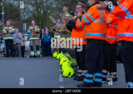 Southend-on-Sea, Royaume-Uni. 16 avril 2020. Les pompiers de la brigade de pompiers d’Essex et le personnel de patrouille de RAC sont en formation à l’extérieur de l’hôpital Southend lors de l’hommage national « Clap for Carers », honorant le personnel du NHS et les travailleurs de première ligne pendant la pandémie de COVID-19. Les casques jaunes sont soigneusement placés entre les rangées de membres du personnel dans un équipement de haute visibilité, tandis que les membres du public applaudissent en arrière-plan. La scène reflète la solidarité communautaire et l'appréciation des services d'urgence et des travailleurs de la santé. Penelope Barritt/Alamy Live News Banque D'Images