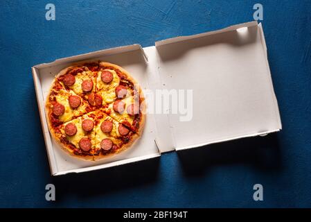 Pizza salami vue de dessus dans sa boîte de carton de livraison. Pizza chaude coupée en 6 portions. Sortez la nourriture. Système de livraison de pizza Banque D'Images