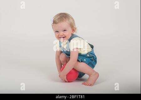 Adorable jeune fille de 18 mois souriante tout en tenant une balle rose dans le studio de photographie de son mama à Playa Del Rey, Californie. Banque D'Images