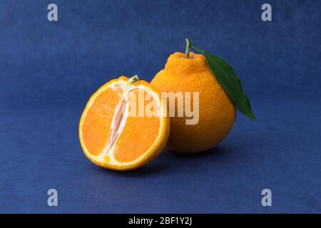 Coupe transversale avec Hallabong orange sur fond bleu. Fruits vus de l'avant. (Corée, spécialités de l'île de Jeju) Banque D'Images