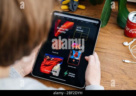Paris, France - 16 avril 2020 : femme regardant sur le site Internet d'Apple Computers sur une tablette iPad Pro dans un environnement de salle présentant les nouvelles spécifications iPhone se Banque D'Images