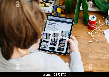 Paris, France - 16 avril 2020 : présenter un nouvel iPhone se avec une femme iOS 13 regardant sur le site Internet d'Apple Computers sur une tablette iPad Pro dans l'environnement de la chambre présentant un nouvel iPhone se avec Banque D'Images