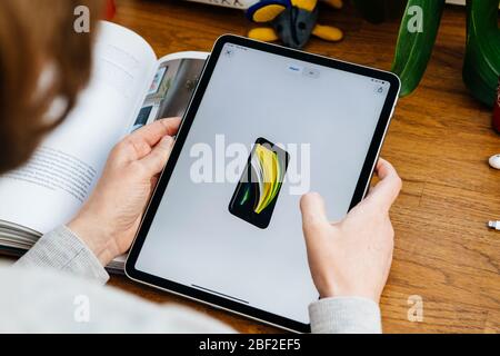 Paris, France - 16 avril 2020 : femme regardant sur le site Internet d'Apple Computers sur une tablette iPad Pro dans l'environnement de la chambre présentant le nouvel iPhone se avec Banque D'Images