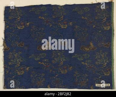 Fragment. Motif de dragons, formes florales et nuages volants dans des lissages supplémentaires de soie dorée, verte, rouge, bleu clair et fils d'or sur terre de sergé bleu foncé. Banque D'Images