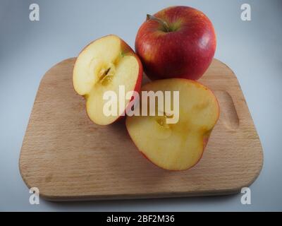 Deux pommes rouges sur une planche à découper, une divisée en deux parties Banque D'Images