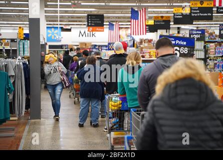 Cromwell, CT / USA - 20 mars 2020: Perple attendre dans de longues lignes pour une chance d'acheter du papier de toilette ou de l'aseptisant chez Walmart (se concentrer sur l'homme avec bac Banque D'Images