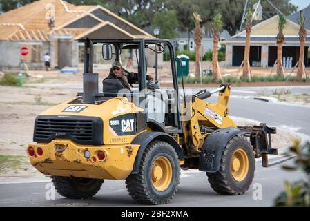 Le conducteur de tracteur déplace l'équipement si nécessaire pour le développement de la construction de nouvelles maisons dans le centre de la Floride pendant que le coronavirus reste à la maison Banque D'Images