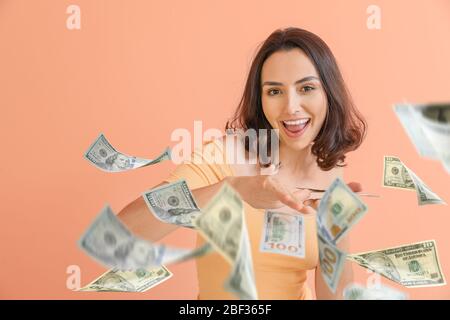 Belle jeune femme avec de l'argent volant sur fond couleur Banque D'Images