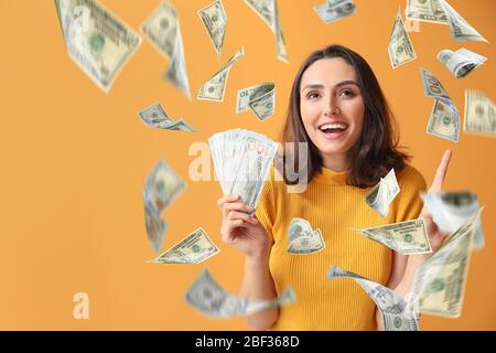 Belle jeune femme avec de l'argent volant sur fond couleur Banque D'Images