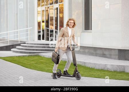 Jeune homme d'affaires avec scooter de coup d'enfant à l'extérieur Banque D'Images