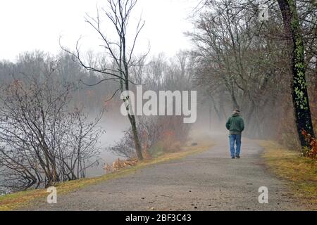 Image conceptuelle d'un homme solitaire et vieillissant prenant une distance sociale à pied seul à travers la brume Banque D'Images