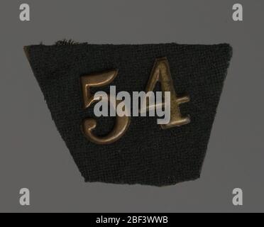 Le numéro 54 en laiton. Le numéro de laiton « 54 » est attaché à un fragment de carton recouvert de tissu d'un kepi, qui semble désigner un 54ème régiment de l'armée américaine. Banque D'Images