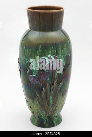 Vase. Corps en faïence rouge. Forme ovoïde allongée, pied évasé, col évasé. Corps appliqué avec iris moulé avec glacis pourpre et nénuphars blancs, les deux avec le feuillage émergeant des lignes d'eau stylisées. Banque D'Images