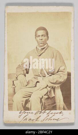 Carte de visite du Sgt Jacob Johns 19ème USCT. Cette carte de visite est accompagnée d'un imprimé photographique représentant le Sergent Jacob Johns assis, face au spectateur, les mains gantées reposant sur ses genoux. Son coude droit repose sur une petite table latérale circulaire, alors qu'il semble tenir son bras gauche vers le haut sans soutien. Banque D'Images