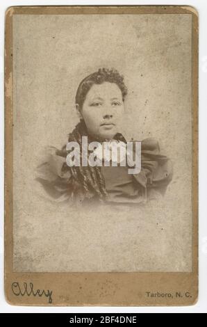 Carte de cabinet d'un membre non identifié de la famille Vass. Portrait photo noir et blanc d'une femme avec de longs cheveux attachés avec des boucles placées sur son épaule droite. Elle porte une robe sombre à manches bouffantes et une volants blancs à encolure en dentelle. Banque D'Images