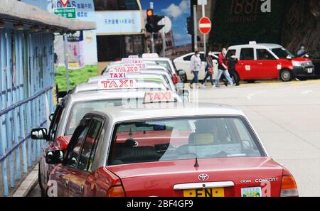 Taxis de confort Red Toyota de Hong Kong stationnés sur une longue ligne à TST, Hong Kong. Banque D'Images