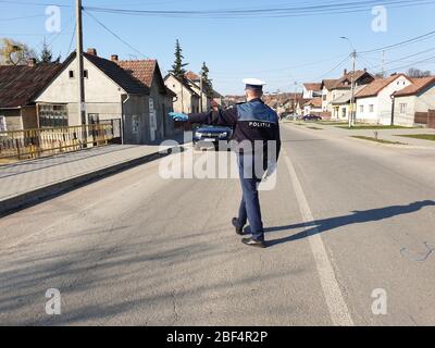 L'agent de police, la police de la circulation roumaine (Politia Rutiera) avec des gants chirurgicaux et un masque, arrête les voitures pour vérifier le permis de conduire et les papiers. Covid 19 Banque D'Images