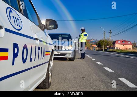 L'agent de police, la police de la circulation roumaine (Politia Rutiera) avec des gants chirurgicaux et un masque, arrête les voitures pour vérifier le permis de conduire et les papiers. Covid 19 Banque D'Images