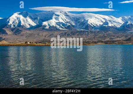 Nuages au-dessus de la montagne Kongur. Lac Karakul, Province du Xinjiang. Les touristes et les yourtes kirghizes en arrière-plan. Banque D'Images