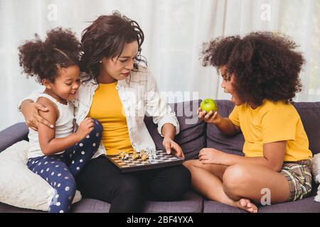 Une mère seule bonne garde, enseignant à ses enfants d'être génie et les petites filles intelligentes apprendre à jouer jeu d'échecs manger des fruits pour la santé. Banque D'Images