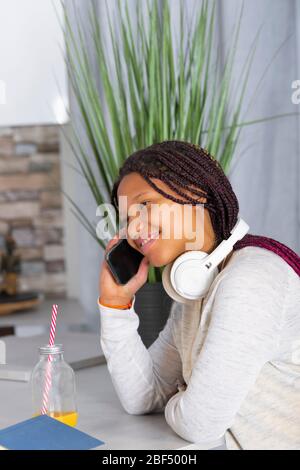 une adolescente utilisant le téléphone dans le bar de cuisine, la communication d'ami et le concept de relation Banque D'Images