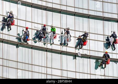 Des nettoyeurs de fenêtres en hauteur sont à l'œuvre sur la façade vitreuse d'un gratte-ciel à Milan, en Italie Banque D'Images