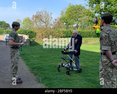 (200417) -- LONDRES, le 17 avril 2020 (Xinhua) -- Tom Moore(C), fonctionnaire à la retraite et vétéran de la seconde Guerre mondiale, s'entretient avec des membres du premier Bataillon, The Yorkshire Regiment, après avoir terminé son tour final dans son jardin de Bedfordshire, Grande-Bretagne, le 16 avril 2020. Le vétéran de guerre de 99 ans a amassé plus de 12 millions de livres (15 millions de dollars américains) pour le National Health Service (NHS) en bouclant 100 tours de son jardin. Avec l'aide d'un cadre de marche, Tom Moore, un fonctionnaire à la retraite et un vétéran de la seconde Guerre mondiale, avait prévu de faire 100 tours de son jardin dans le Bedfordshire, Banque D'Images