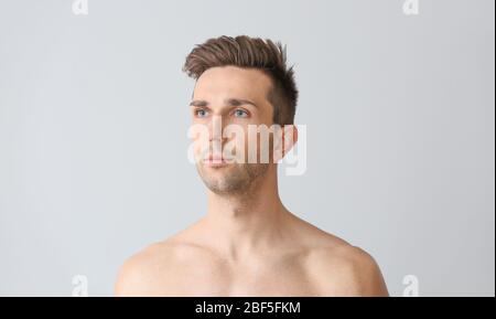 Beau jeune homme sur fond clair. Concept de chirurgie plastique Banque D'Images