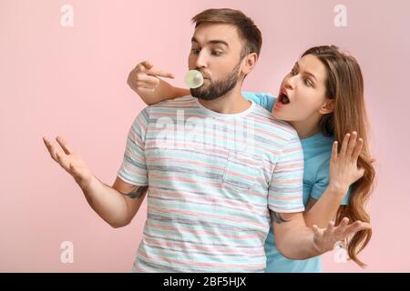 Drôle de jeune couple avec chewing-gum sur fond de couleur Banque D'Images