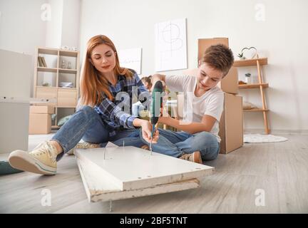 Mère et son petit fils assemblant des meubles à la maison Banque D'Images