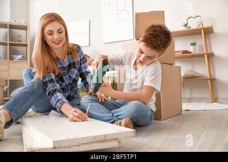 Mère et son petit fils assemblant des meubles à la maison Banque D'Images