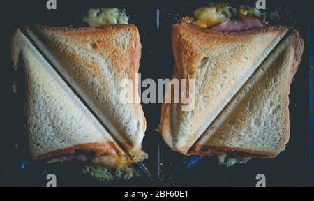 Toasts au jambon et au fromage grillés en triangles sur le grille-pain Banque D'Images