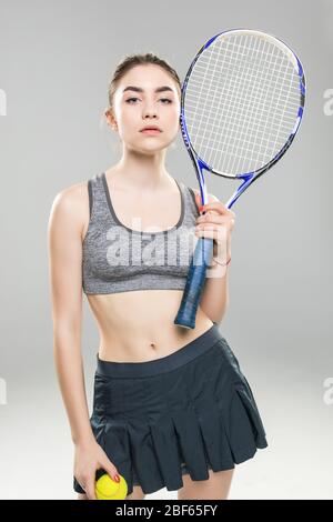 Portrait d'un joueur de tennis woman holding racket et isolé sur fond gris à billes Banque D'Images