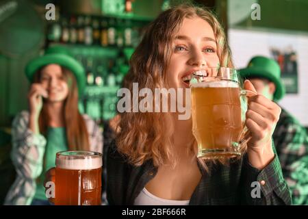 Jeune femme avec bière célébrant la Saint Patrick's Day au pub Banque D'Images