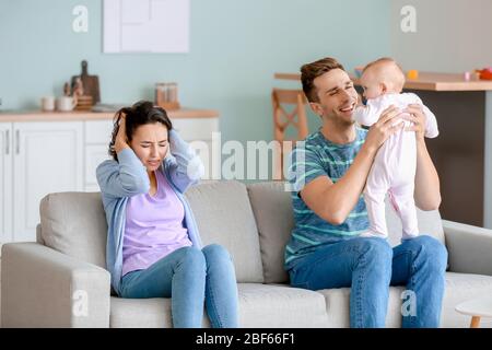 Heureux père avec son bébé et sa femme souffrant de dépression postnatale à la maison Banque D'Images