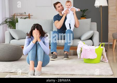 Heureux père avec son bébé et sa femme souffrant de dépression postnatale à la maison Banque D'Images