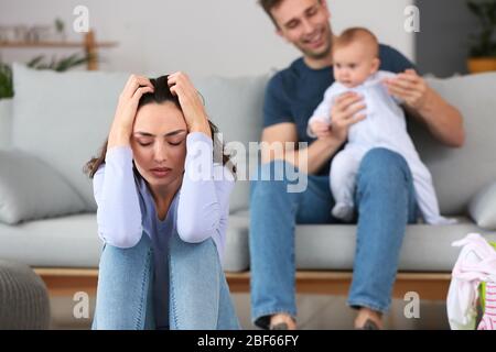 Heureux père avec son bébé et sa femme souffrant de dépression postnatale à la maison Banque D'Images