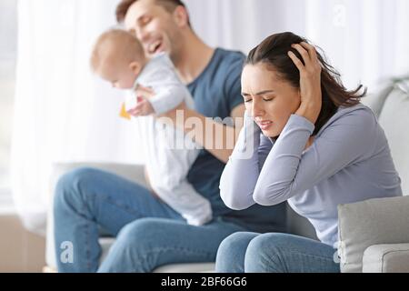 Heureux père avec son bébé et sa femme souffrant de dépression postnatale à la maison Banque D'Images