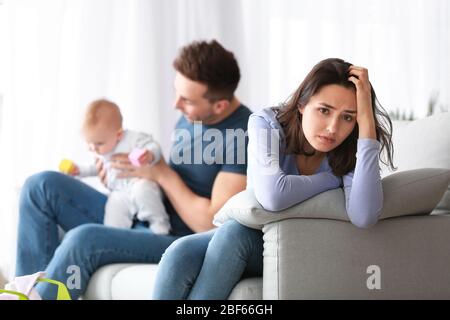 Heureux père avec son bébé et sa femme souffrant de dépression postnatale à la maison Banque D'Images